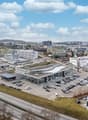 Building complex, multiple buildings, large parking lot, highway in front, green surroundings
