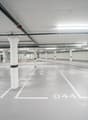 wide parking area, multiple columns, painted white lines, yellow markings, several pipes