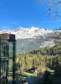 A glass-enclosed building with a view of snow-capped mountains and a forested valley in the background. The building appears to be situated in a scenic, mountainous area.