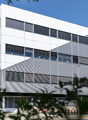 A multi-story office or commercial building with a modern, minimalist design. The building has a white exterior with large windows and a prominent entrance.