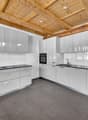 modern kitchen with white cabinets, black countertops, wooden ceiling, built-in oven, sink, faucet, dishwasher, washing machine