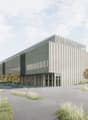 A large modern industrial or commercial building with a rectangular, multi-story design featuring a mix of concrete and glass materials. The building has a sleek, contemporary architectural style with vertical lines and a prominent entrance. The surroundi