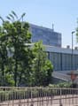 Large white building, several floors, glass windows, surrounded by trees, metal railings