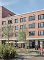 red brick building, multiple windows, ground floor commercial space, parking area