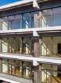 Modern multi-story building with glass facade, balconies, and terraces
