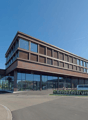 modern office building, large glass facade, brown facade, large parking lot, cars parked in front