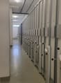 Storage units lined up, with numbers 40-47 on the doors, white walls, metallic beams, and a metal railing.