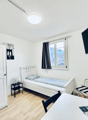 Small room with a bed, bedside table, desk, TV, chair, plant, and wardrobe