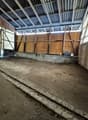 empty room, dirt floor, wooden walls, large open windows, metal roof