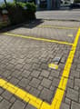 A brick paved parking lot with yellow markings