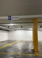 Empty parking lot with yellow lines, white walls, and yellow pillars.