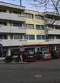 Multi-story building, balconies, yellow exterior, parking lot