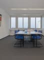 empty room, desk, chairs, flatscreen TV mounted on wall, windows, carpeted floor