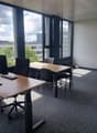 Spacious office with large windows offering a scenic view of the surrounding landscape, including hills and greenery. The office is equipped with desks, chairs, and computer equipment, providing a functional workspace.