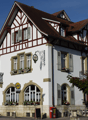 3 story house, white walls, brown roof, brown trim, arched windows, balconies, flower boxes, outdoor seating