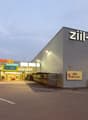 Commercial building, elevated ground, signage, wide parking area, multiple shops