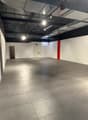 Empty room with white walls, gray floor, two doors, and a red pillar.
