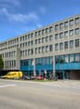 Modern office building with large windows, grey and blue exterior, motorcycles parked in front, street
