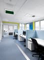 office cubicles with white desks, computer monitors, telephones, and black office chairs