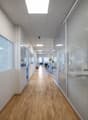 Office hall with wooden floors, glass walls, white walls, modern interior, surveillance camera