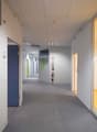 Empty hallway with gray carpet, yellow and white walls, doors, exit signs, fire extinguisher