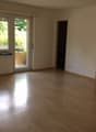 Spacious living room with hardwood floors, large windows overlooking a balcony or terrace, and neutral-colored walls.