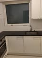modern kitchen with black counter tops, electric stove, built-in oven, sink, and a window