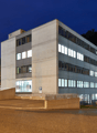 3 story office building, white walls, glass windows, front parking lot, blue signs, street light