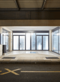 Empty entrance with double doors, tiled floor, large windows, concrete walls, small stone planter