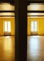 large empty room, wooden floor, yellow walls, windows, radiators