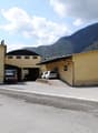 Large yellow building with multiple garages, vehicles parked in front, mountains in the background