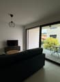 modern apartment, glass wall, couch, flat screen tv, balcony with table and chairs, hardwood floor