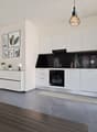open kitchen with modern furniture, light gray marble flooring, black countertop, oven, dishwasher, several decorative framed pictures on wall