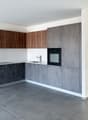 modern kitchen with gray cabinets, white countertops, black oven, wooden shelves, tiled floor