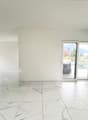 large open space, white marble flooring, white walls, large sliding glass doors, balcony, view of mountains