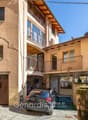 3 story house, beige walls, brown door, balcony, car parked in garage