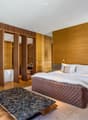 Master bedroom with wooden walls, large bed, bathtub, wooden chair, wooden table, wooden floor, white ceiling
