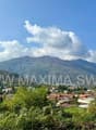 A panoramic view of a town with buildings, mountains, and a river.