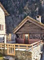 Rustic log cabin house, wooden terrace, stone wall, surrounding mountain