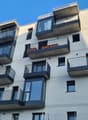 Multi-story apartment building with balconies, modern architectural design, and large windows