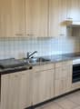 A kitchen with wooden cabinets, granite countertops, a sink, oven, dishwasher, and a window.