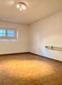empty room, white walls, wooden floor, radiator, two windows, ceiling light