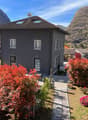 2-story house with a tiled roof, surrounded by colorful autumn foliage and landscaped gardens, set against a backdrop of mountains