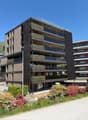 Modern apartment building with multiple floors, balconies, and green plants on the exterior walls