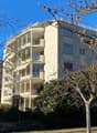 large multistory apartment building with balconies, cream-colored exterior, windows with shutters