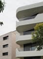 modern apartment building, curved balconies, glass railings, beige ground floor, white upper floors