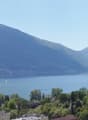 Mountain lake view, buildings, trees, mountains in the distance, clear blue sky