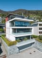 Modern 3-story house, glass facade, multiple balconies, mountain view