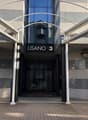 Modern building entrance with glass doors, metal frame, and a sign reading 'LISANO 3'. The entrance is flanked by two lamps.