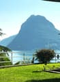 overlooking a mountain and lake, with a metal railing, street lamp, and lush greenery
